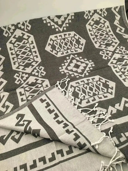 Gray and white Jacquard peshtemal with geometric patterns and fringed edges, folded on a light surface.