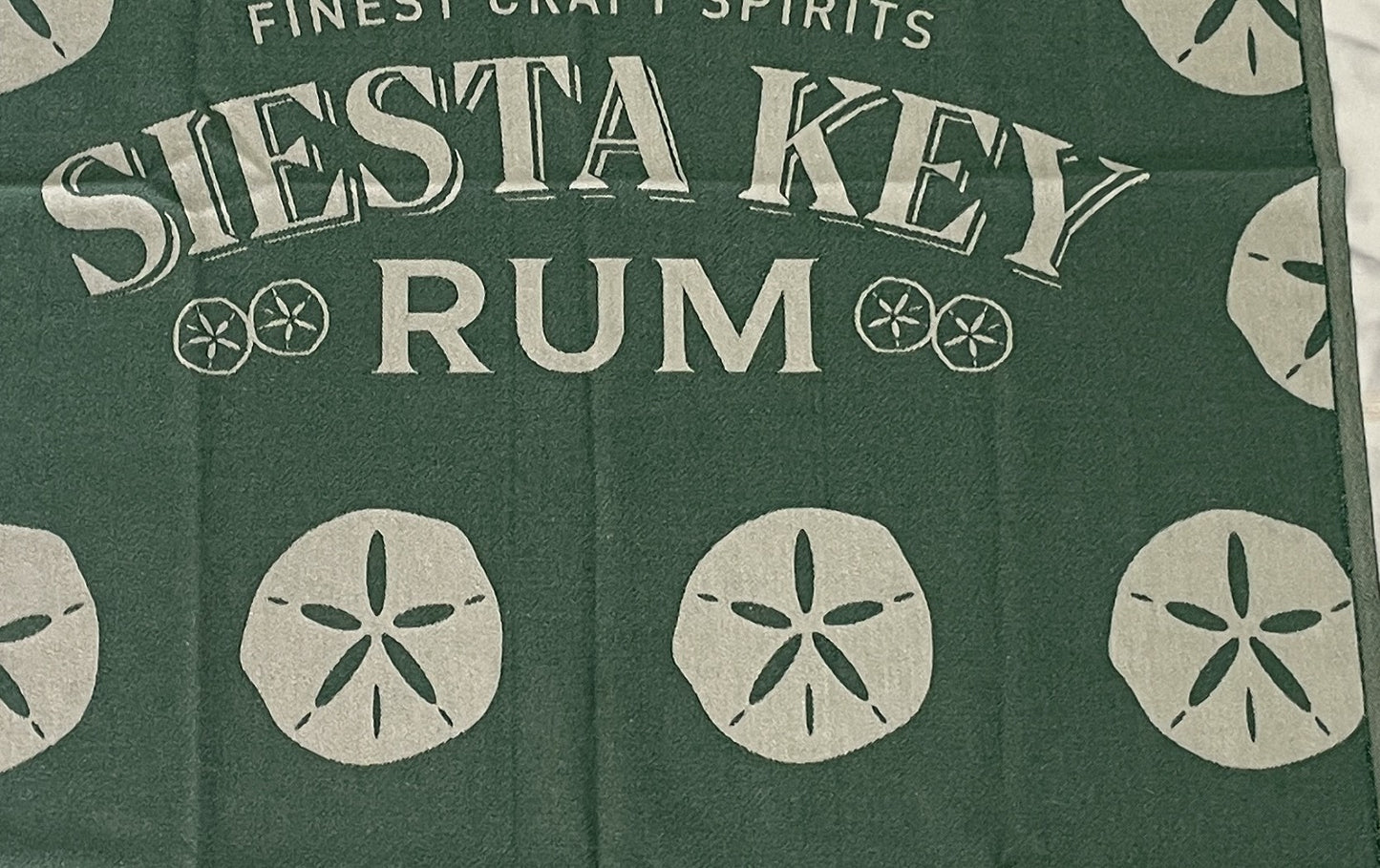 Jacquard-woven Turkish towel with Siesta Key Rum wordmark and sand dollar motif, detail crop