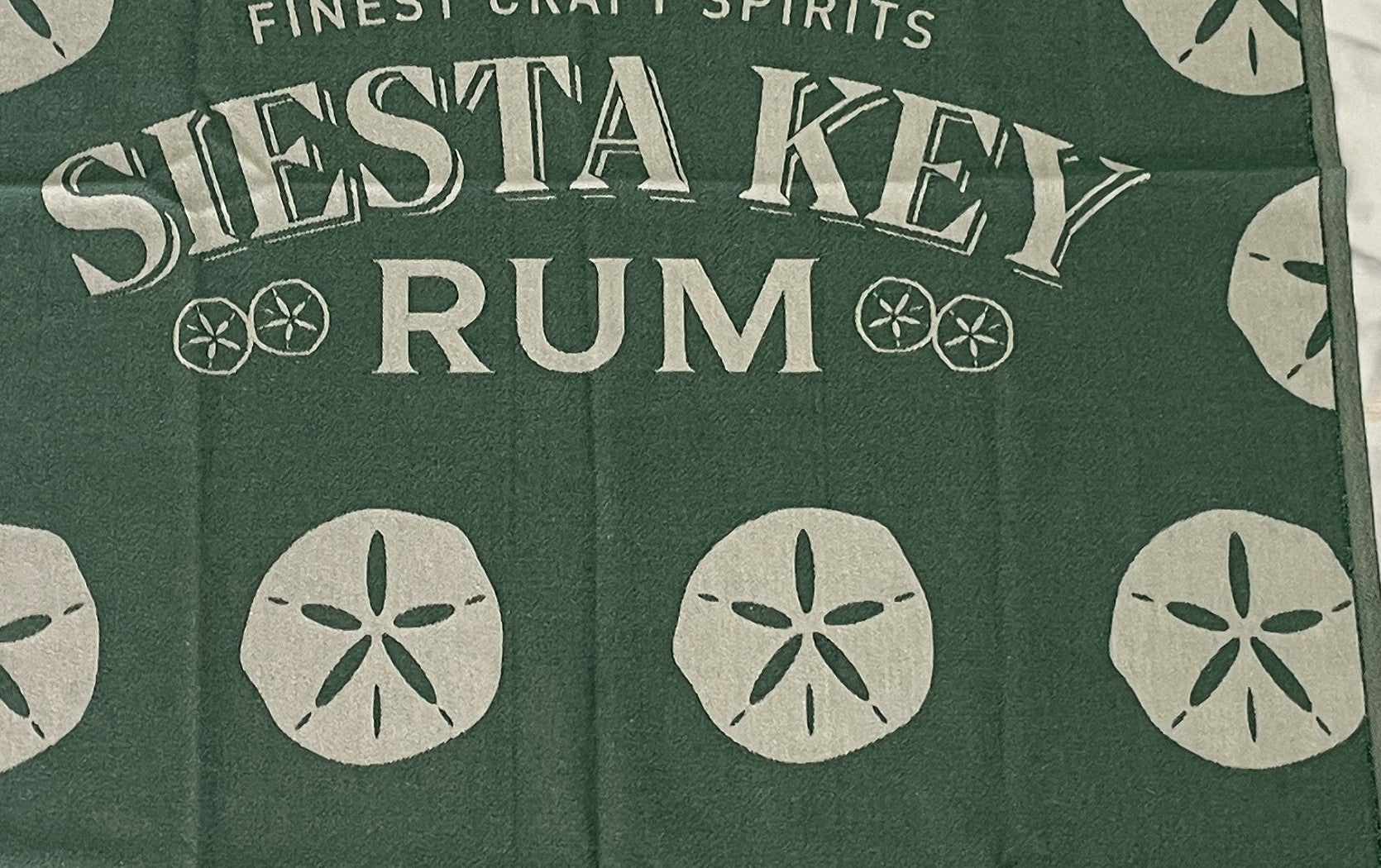 Jacquard-woven Turkish towel with Siesta Key Rum wordmark and sand dollar motif, detail crop